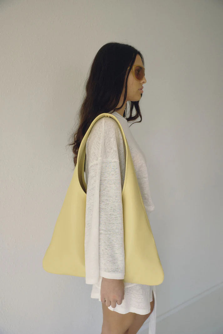 Woman holding a yellow tote bag against a plain background leather bag canada Vancouver Paloma