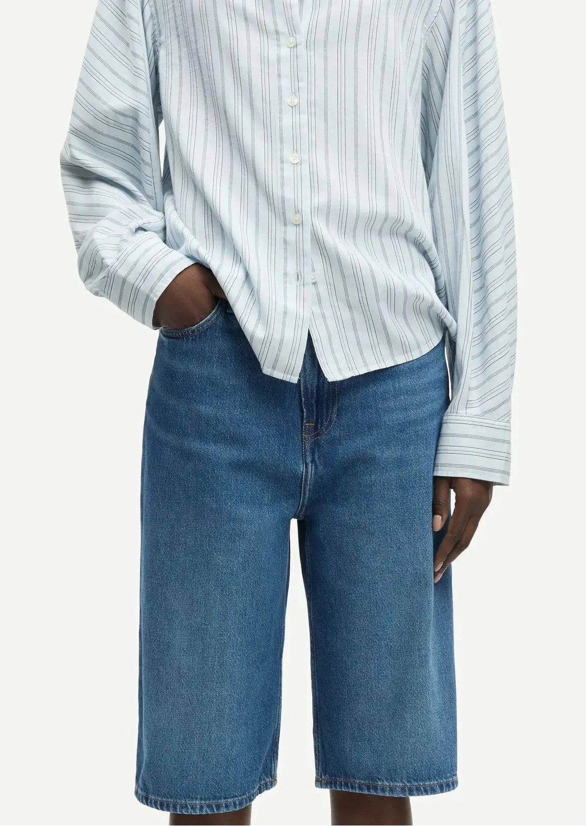 Woman wearing a light blue striped shirt and blue jeans on a white background jorts west Vancouver paloma sale samsoe samsoe