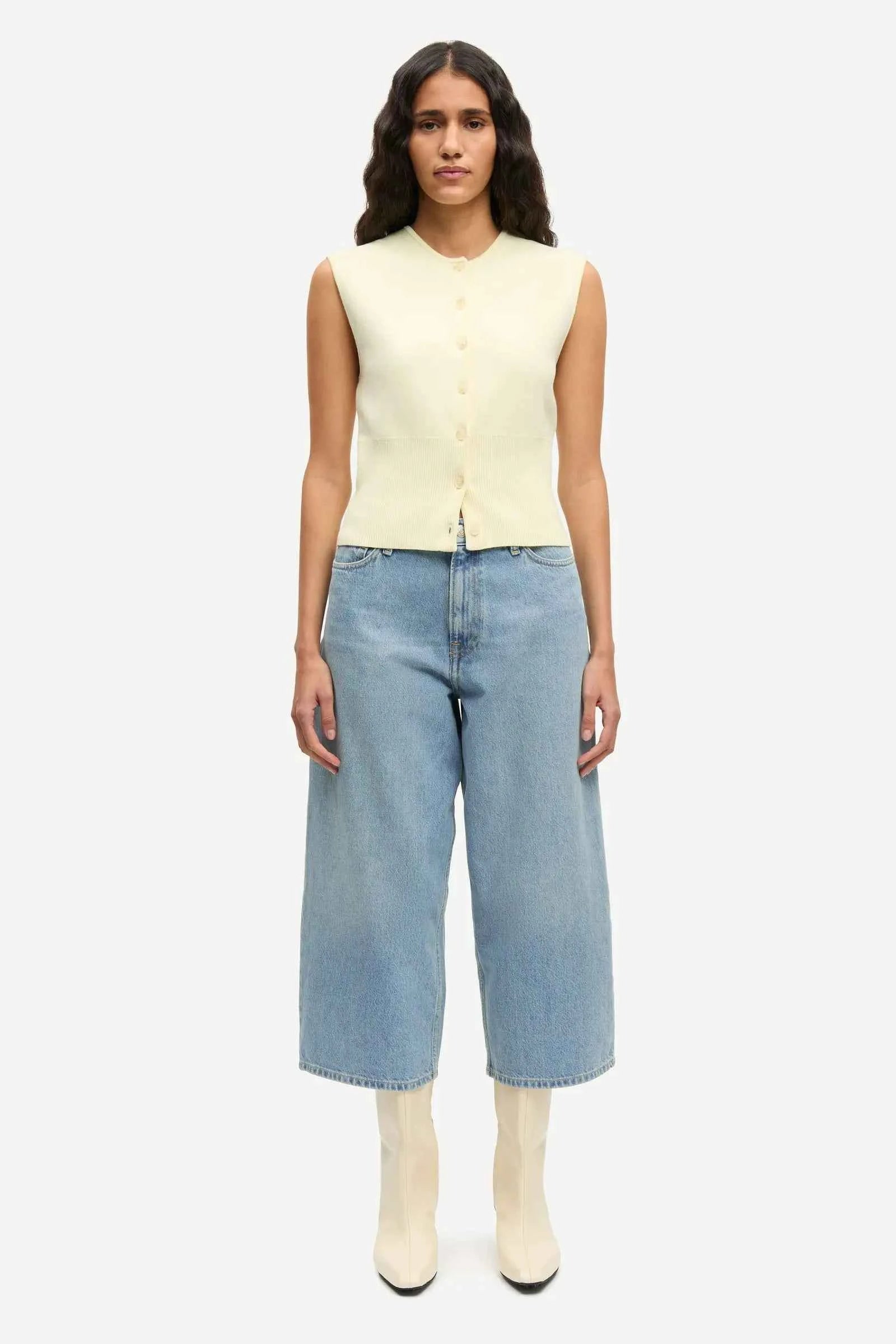 Woman wearing a light yellow sleeveless top and blue jeans on a white background samsoe samsoe sale paloma vancouver